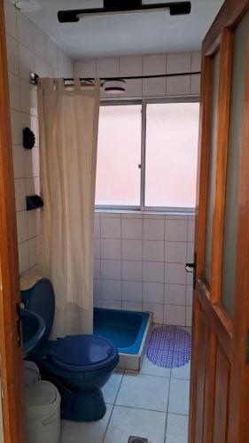 a bathroom with a blue toilet and a tub at Departamento cómodo en Oruro in Oruro