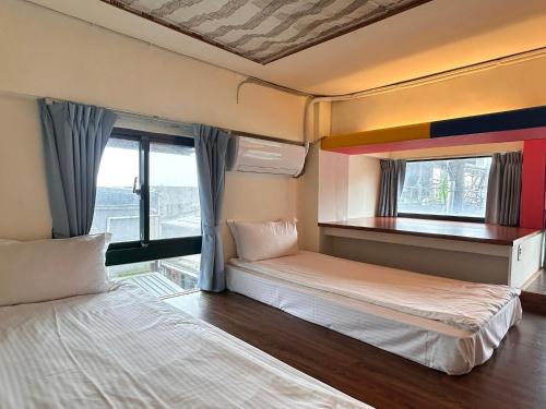 two beds in a room with a window at Old Street Seaview Homestay in Jiufen
