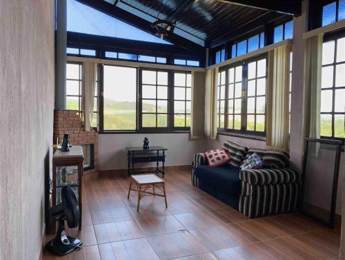 a large living room with a couch and windows at Chácara das Pedras Acolhedor, Alegria, Refúgio in Piracaia