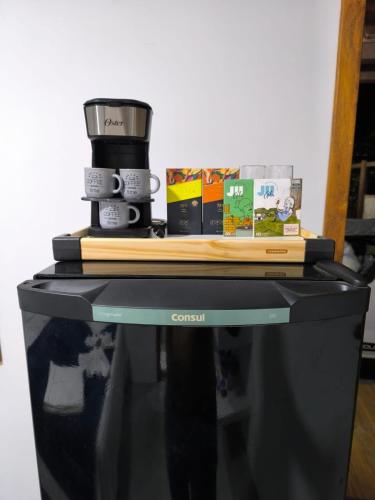 a coffee maker and books sitting on top of a microwave at Canto do Mar Suíte in Marau