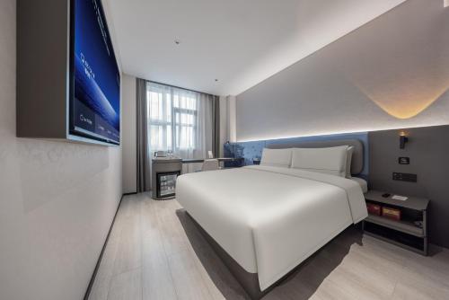 a bedroom with a large white bed and a tv at Atour Light Hotel Shenzhen North Railway Station Subway Station in Shenzhen