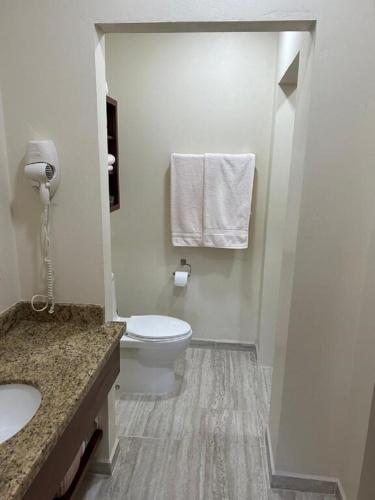 a white bathroom with a toilet and a sink at Paradise Inn Placencia in Placencia Village