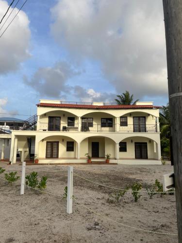 a large white building with a palm tree at Paradise Inn Placencia in Placencia Village