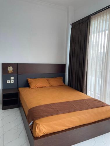 a bed in a bedroom with a large window at Laika Homestay in Gondowulung