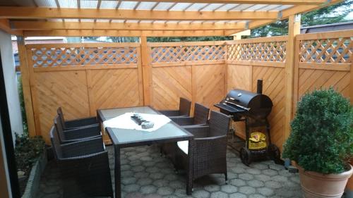 eine Terrasse mit einem Tisch, Stühlen und einem Grill in der Unterkunft Ostfriesisches Landhaus in Wittmund