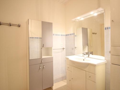 Un baño blanco con lavabo y espejo. en Bel appartement T3 avec garage privé, à 200m du centre du Mont-Dore, 6 couchages, animaux acceptés - FR-1-415-43, en Le Mont-Dore