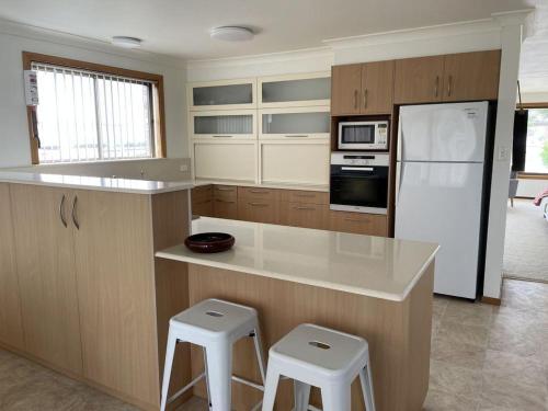 a kitchen with a counter and a refrigerator and stools at Drift at Harrington in Harrington