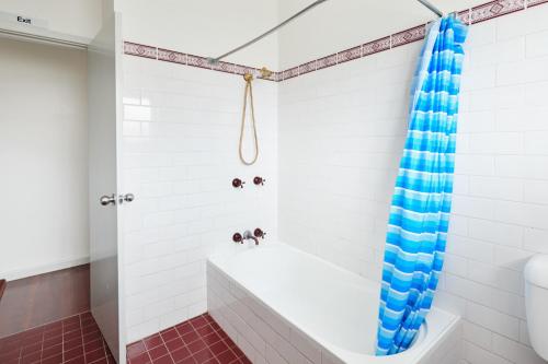 a bathroom with a white tub and a blue shower curtain at The Greenhouse at Harrington in Harrington
