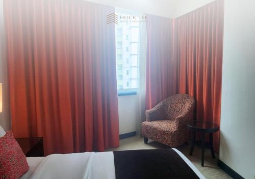 a bedroom with a bed and a chair and a window at Hock Lee Hotel & Residences in Kuching