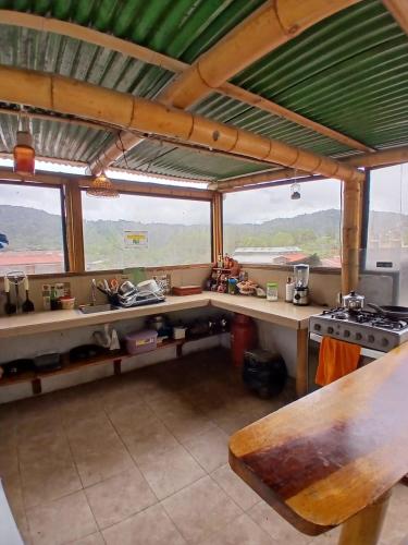 a kitchen with a table and a stove and windows at Golden Bird in Mindo