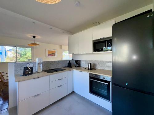 une cuisine avec des armoires blanches et un réfrigérateur noir dans l'établissement Grande Maison Familiale Proche Plage, Piscines et Commerces – Idéal pour 8 Personnes - FR-1-323-546, à Saint-Jean-de-Monts