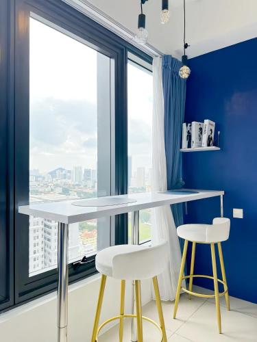 a table and two stools in a room with a large window at Tropicana 218 Macalister Penang in George Town