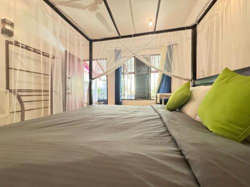 Un dormitorio con una cama grande con almohadas verdes. en Aira Place, en Weligama