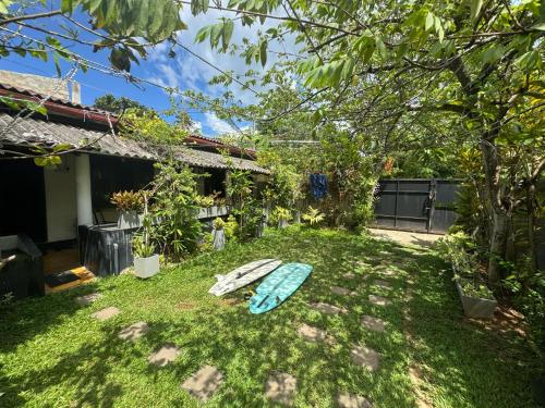 un patio con una tabla de surf sobre la hierba en Aira Place, en Weligama