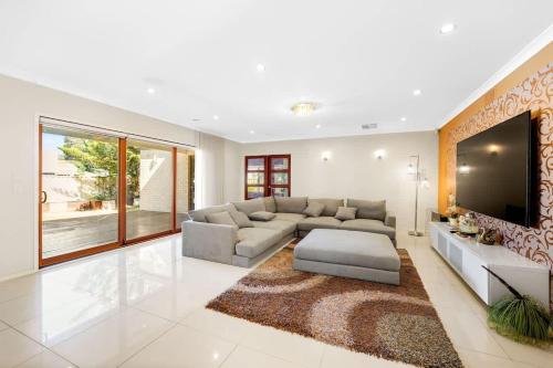 a large living room with a couch and a tv at Rustic Point Cook Family Home near Sanctuary Lakes in Point Cook