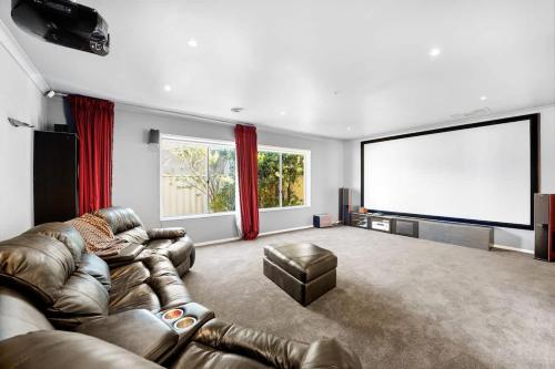 a large living room with a couch and a screen at Rustic Point Cook Family Home near Sanctuary Lakes in Point Cook