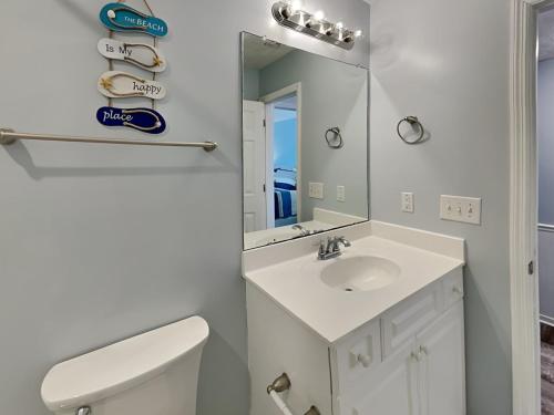 a white bathroom with a sink and a mirror at The Twisted Pelican in Surf City