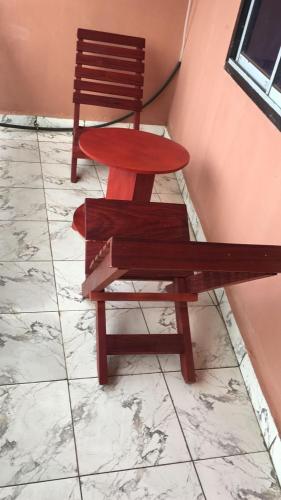 a bench and a chair sitting on a tiled floor at Papi House in Limbe