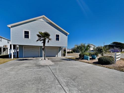 a house with a palm tree in front of a driveway at Bellcove in Surf City