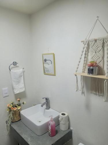 a white bathroom with a sink and a shelf at Céntrico, con alberca y estacionamiento in Guadalajara
