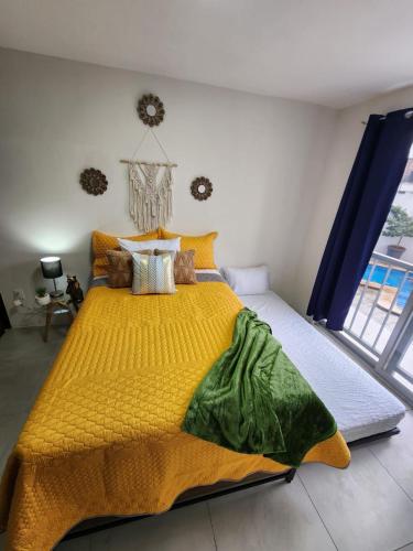 a bedroom with a bed with a yellow blanket at Céntrico, con alberca y estacionamiento in Guadalajara