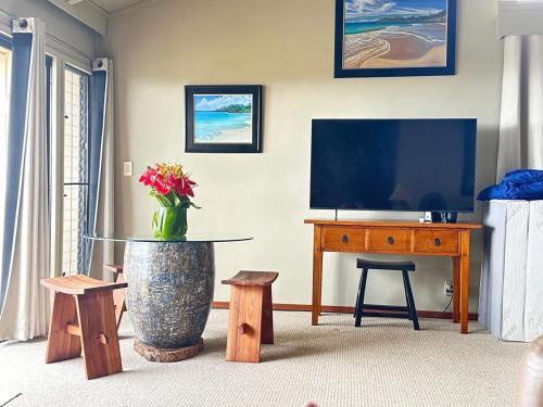 a living room with a television and a vase of flowers at Best Ocean and Mountain View! in Waikoloa Village