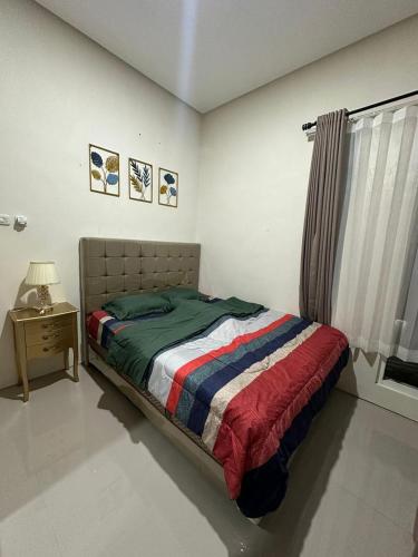 a bedroom with a bed and a table and a window at Villa Sunrise F1 in Malang