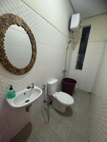 a bathroom with a toilet and a sink and a mirror at Villa Sunrise F1 in Malang