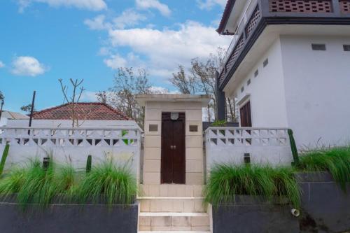 a white house with a wooden door and grass at Aurora Holiday House Kintamani in Kintamani