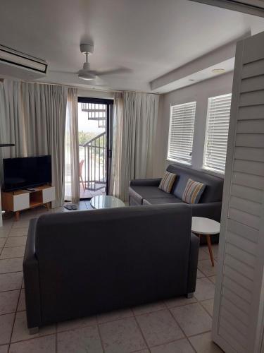 a living room with a couch and a tv at Stylish 1 Bedroom with Private Rooftop Spa at the Aegean in Mooloolaba