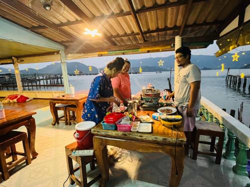 a group of people preparing food on a table on a boat at Happy Fuji Homestay in Ko Phrao Nai