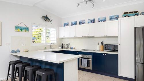 a kitchen with blue and white cabinets and black stools at Water Views on Wallawa in Nelson Bay