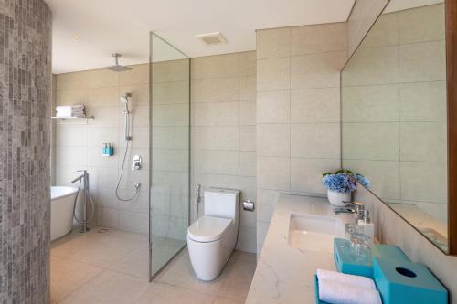 a bathroom with a toilet and a shower and a sink at A La Carte Ha Long Bay Managed by TASECO in Ha Long