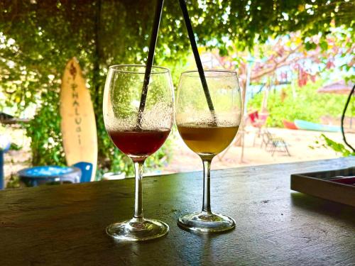 two glasses of wine sitting on a wooden table at Baan Plai Laem Homestay at Koh Paluay in Koh Phaluai