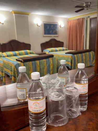 three bottles of water on a table in a hotel room at MariaCristina in San Luis Potosí