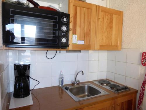 une cuisine avec un évier et un micro-ondes dans l'établissement Studette 2 pers. avec box à skis, Barcelonnette - FR-1-804-52, à Barcelonnette
