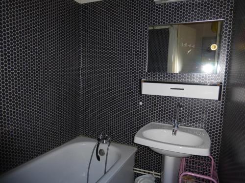 une salle de bain avec un lavabo, une baignoire et un miroir dans l'établissement Studette 2 pers. avec box à skis, Barcelonnette - FR-1-804-52, à Barcelonnette