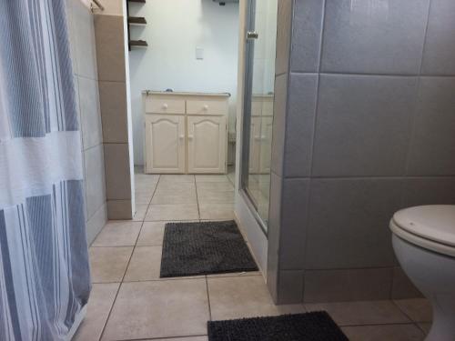 a bathroom with a shower and a toilet and a shower curtain at Beach Rock Cottage in Kiddʼs Beach