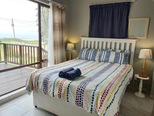a bedroom with a bed with a view of a balcony at Beach Rock Cottage in Kiddʼs Beach