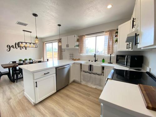a large kitchen with white cabinets and a table at Pax Sacellum Kanab Home for Southern Utah Hiking in Kanab