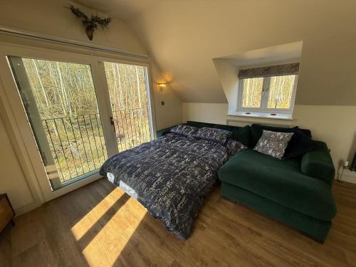 a bedroom with a bed and a green couch at Dukes Flat in Ampney Saint Peter