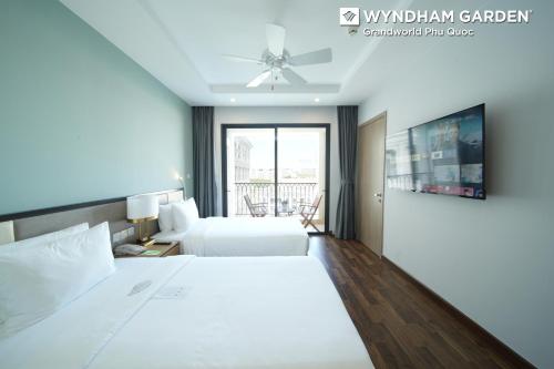 a bedroom with two beds and a ceiling fan at Wyndham Garden Grandworld Phu Quoc in Phu Quoc
