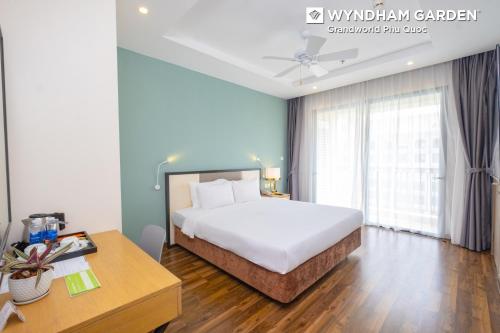 a bedroom with a bed and a desk and a bed at Wyndham Garden Grandworld Phu Quoc in Phu Quoc