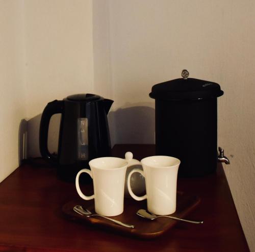 two coffee cups on a table with a coffee maker at Suite de lujo en finca de café in Antigua Guatemala