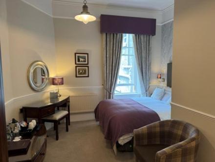 a bedroom with a bed and a desk and a window at Wellwood Manor in Pitlochry