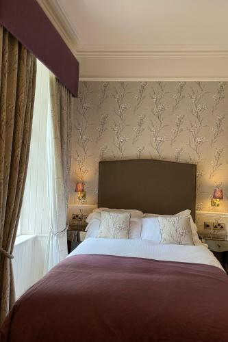 a bedroom with a large bed with a large headboard at Wellwood Manor in Pitlochry