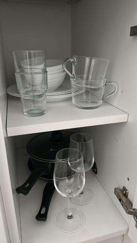two wine glasses and plates on a shelf at ASM - TrainStation Studio Apartment in Scunthorpe