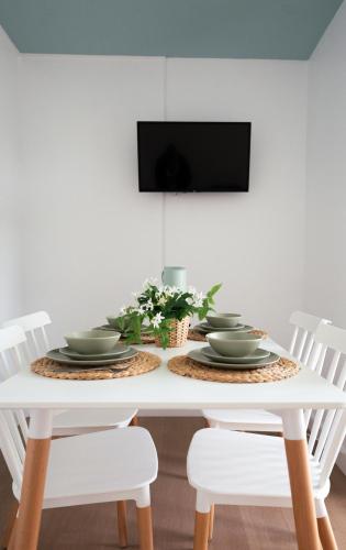 a white dining room table with white chairs and a tv at Nura Houses Magaluf Beach in Magaluf