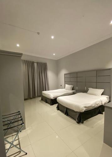two beds in a large room with white tiles at ليلك سويت للشقق المخدومة in Taif