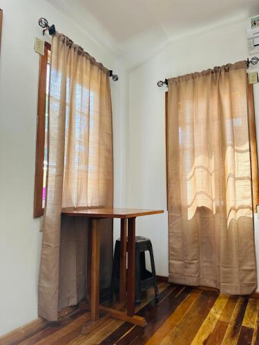 a wooden table in a room with curtains at Silver Sand, Placencia in Placencia Village